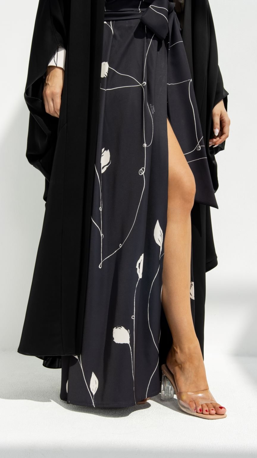 Selected Lines luxury Al Zain Abaya with black and white floral design and side slit showing leg