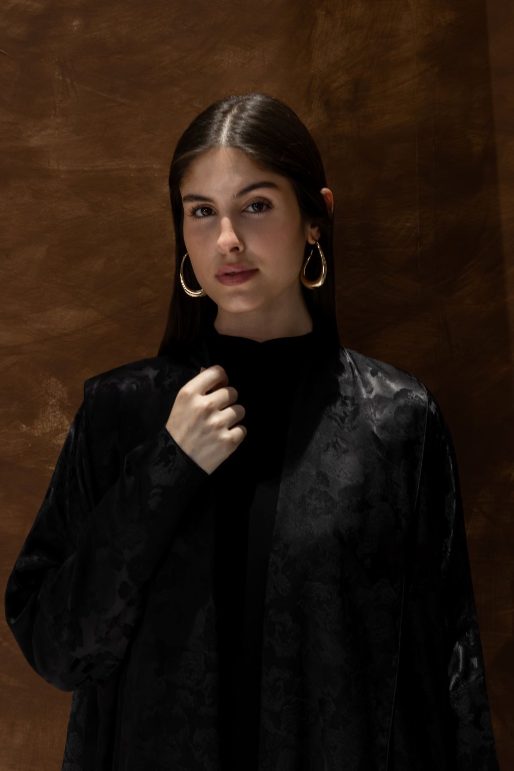 Selected Lines black Bahraini abaya for women with subtle floral pattern worn by model with hoop earrings