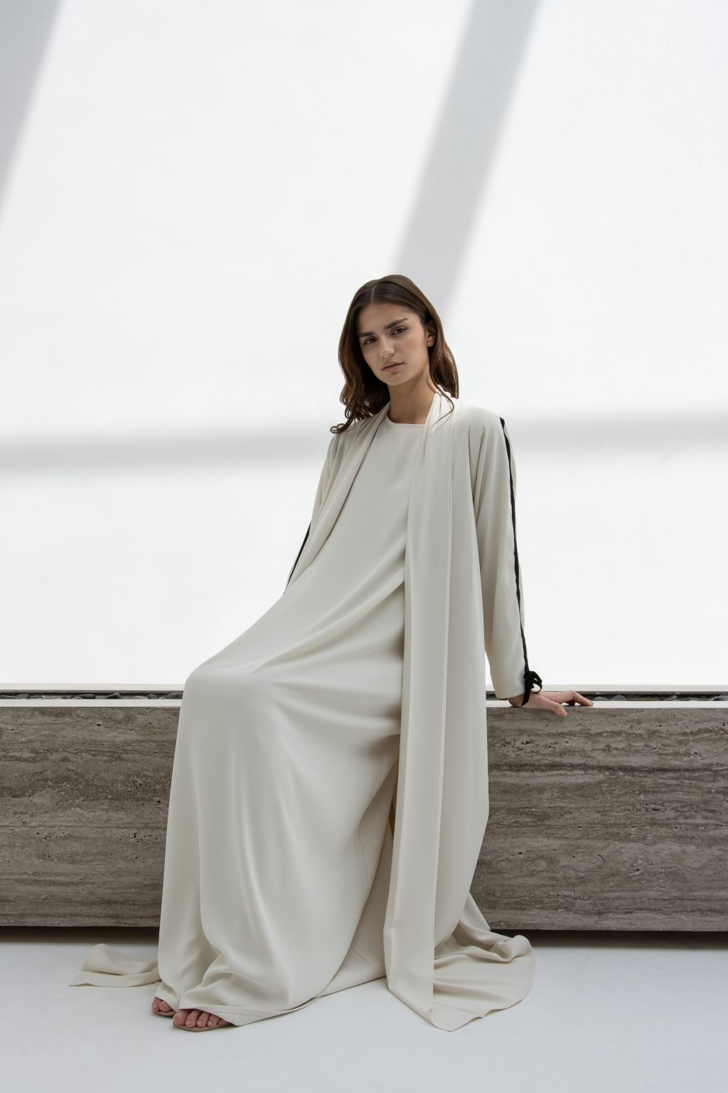 Elegant cream abaya with black velvet ribbon for sewing details on sleeves.