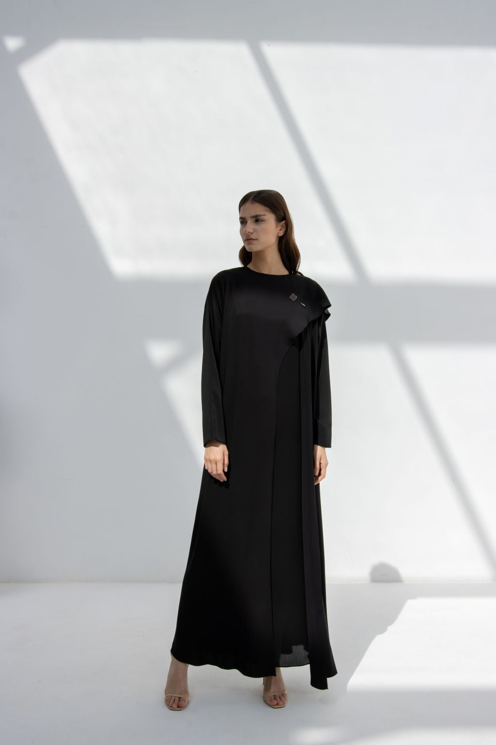Selected Lines elegant flip wing abaya in black worn by model in minimal bright setting