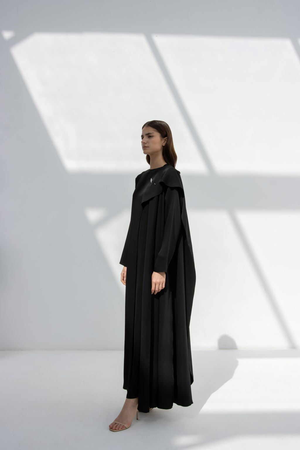 Selected Lines elegant flip wing abaya in black worn by model in minimalist bright studio