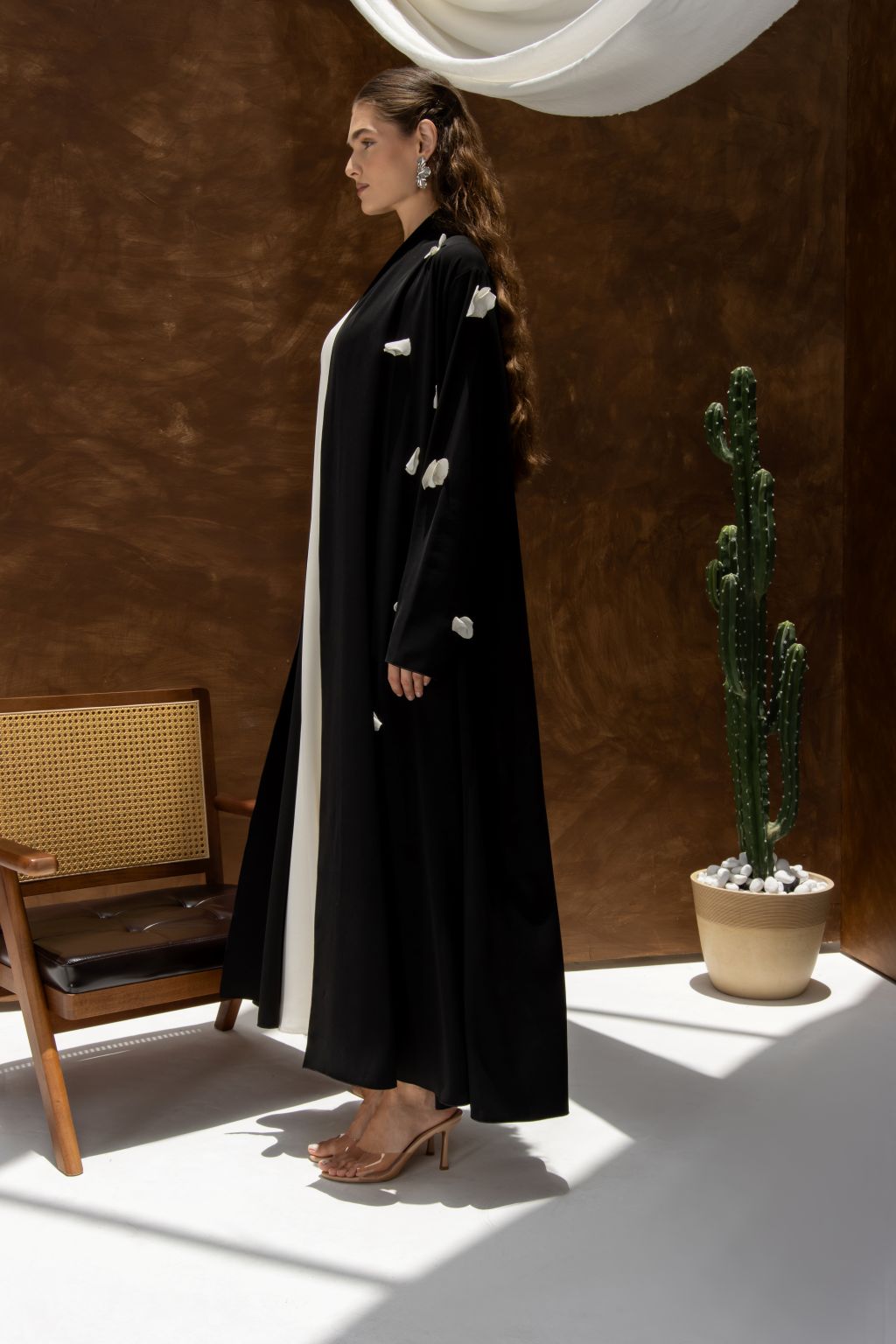 Selected Lines black designer abaya handcrafted details with white accents worn by woman standing indoors