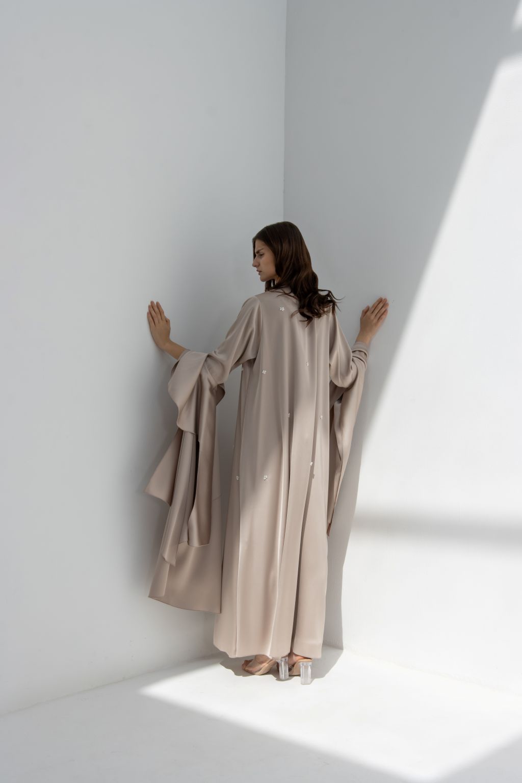 Back view of a woman wearing an elegant seashell dress by Selected Lines standing in a bright corner