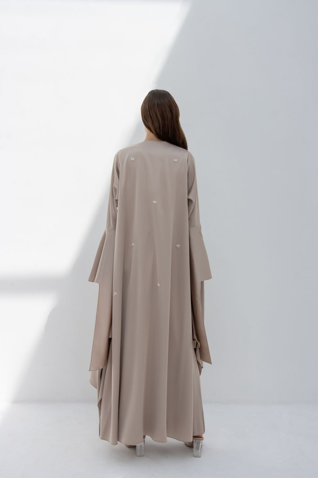 Back view of model wearing elegant seashell dress by Selected Lines in soft beige color