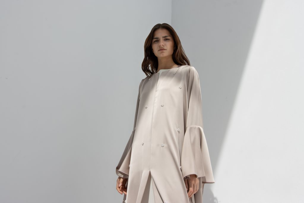 Model wearing a beige elegant seashell dress by Selected Lines with long bell sleeves and minimal design