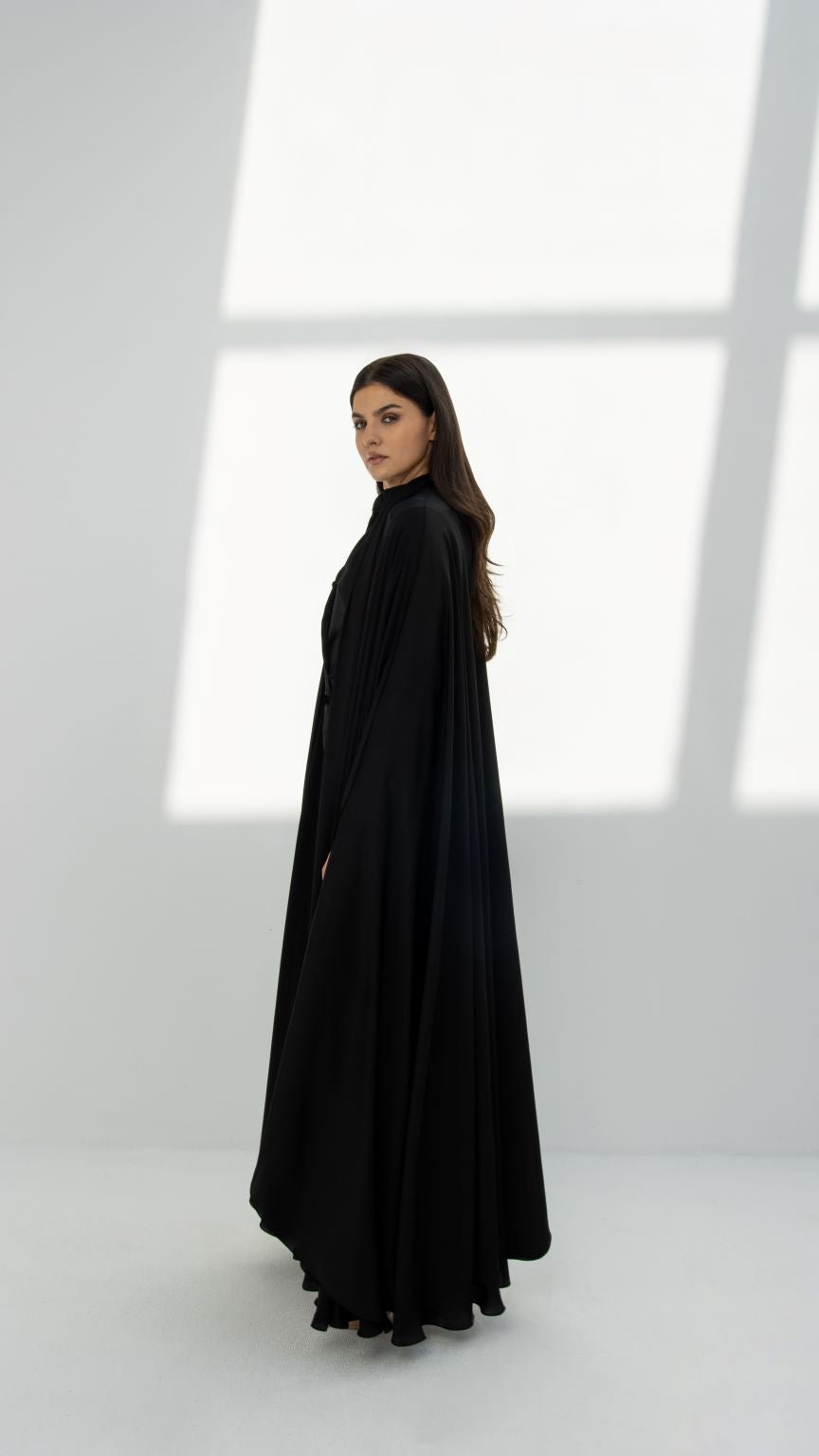 Model wearing a black abaya with elegant abaya designs in a minimalist studio setting
