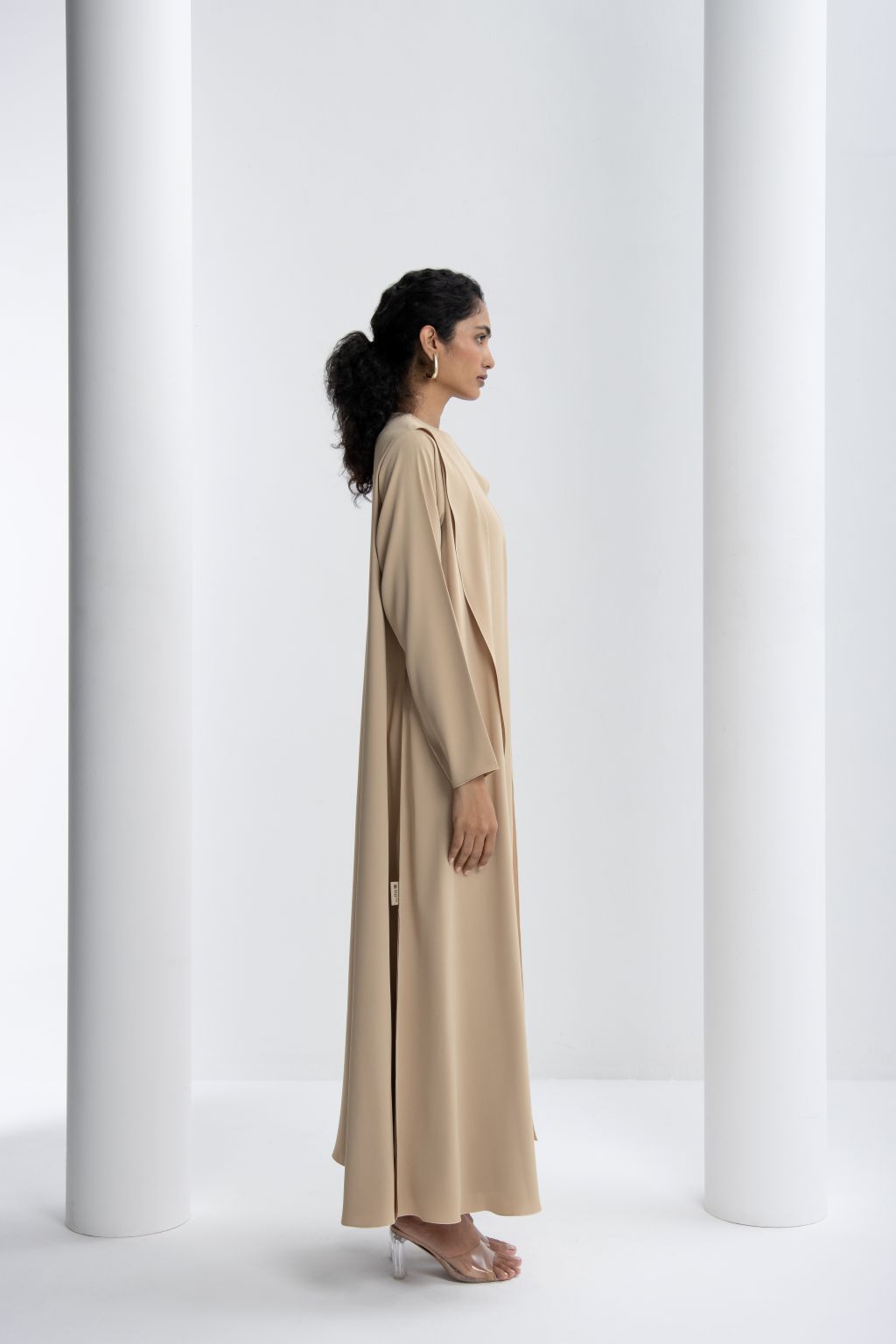 Elegant abaya for women in beige with a flowy design, showcasing a side profile view