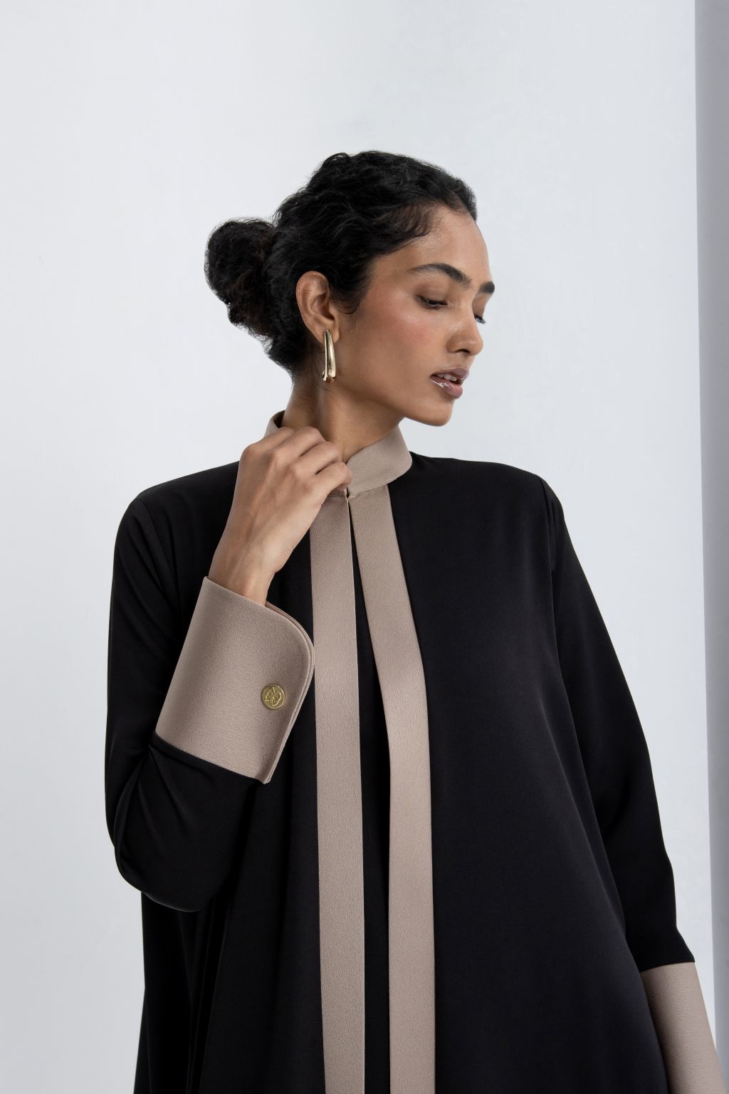 Stylish model wearing an elegant black modest abaya with contrasting beige collar and cuffs