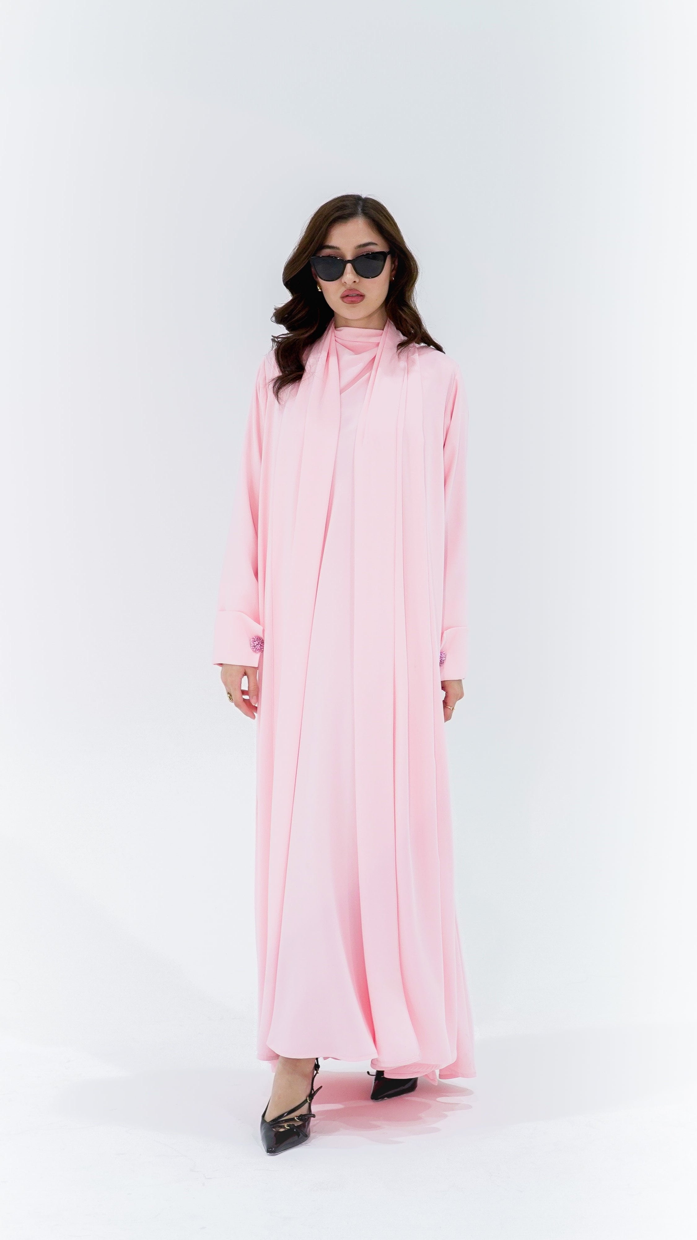 Elegant pearl buttons abaya in soft pink fabric, featuring a flowing design and long sleeves
