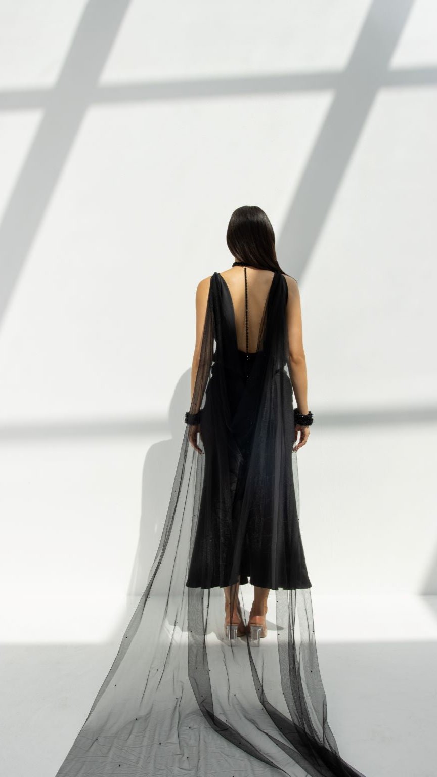 Woman wearing a black Selected Lines high-end choker gown with sheer long train and deep back design