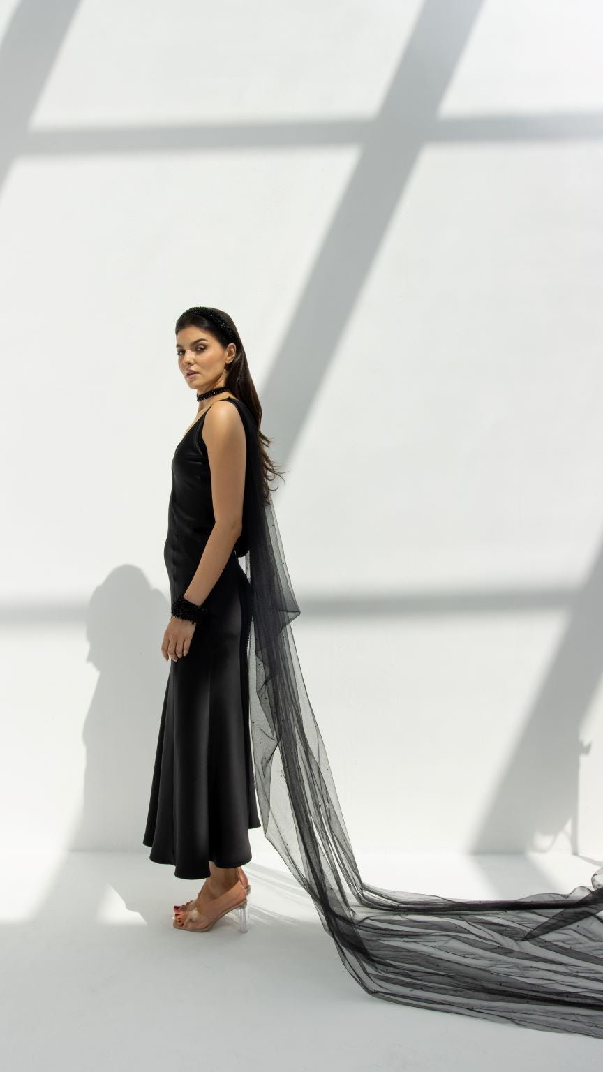 Selected Lines black high-end choker gown with long sheer train worn by model in minimalist light background