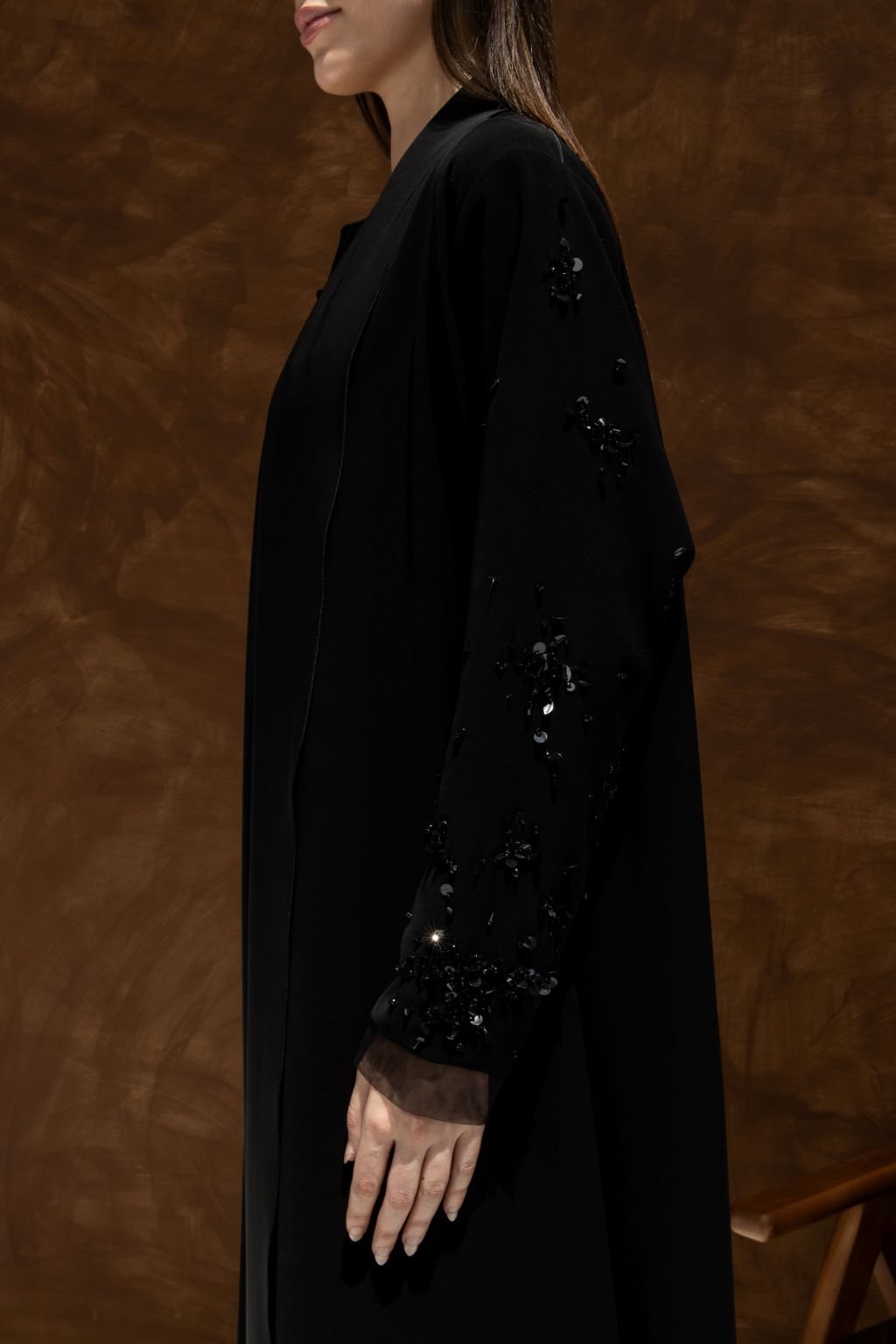 Selected Lines black La Lueur abaya Set featuring embellished sleeves on a model against a brown background
