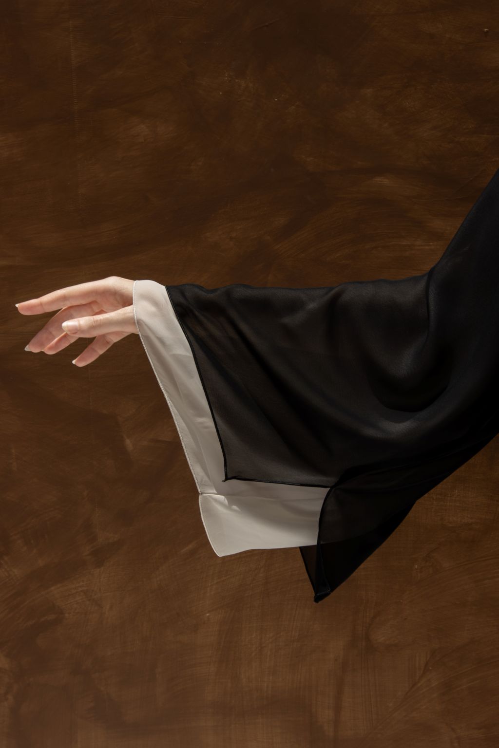 Selected Lines Layered Grace Abaya sleeve detail with black and white layered fabric on brown background