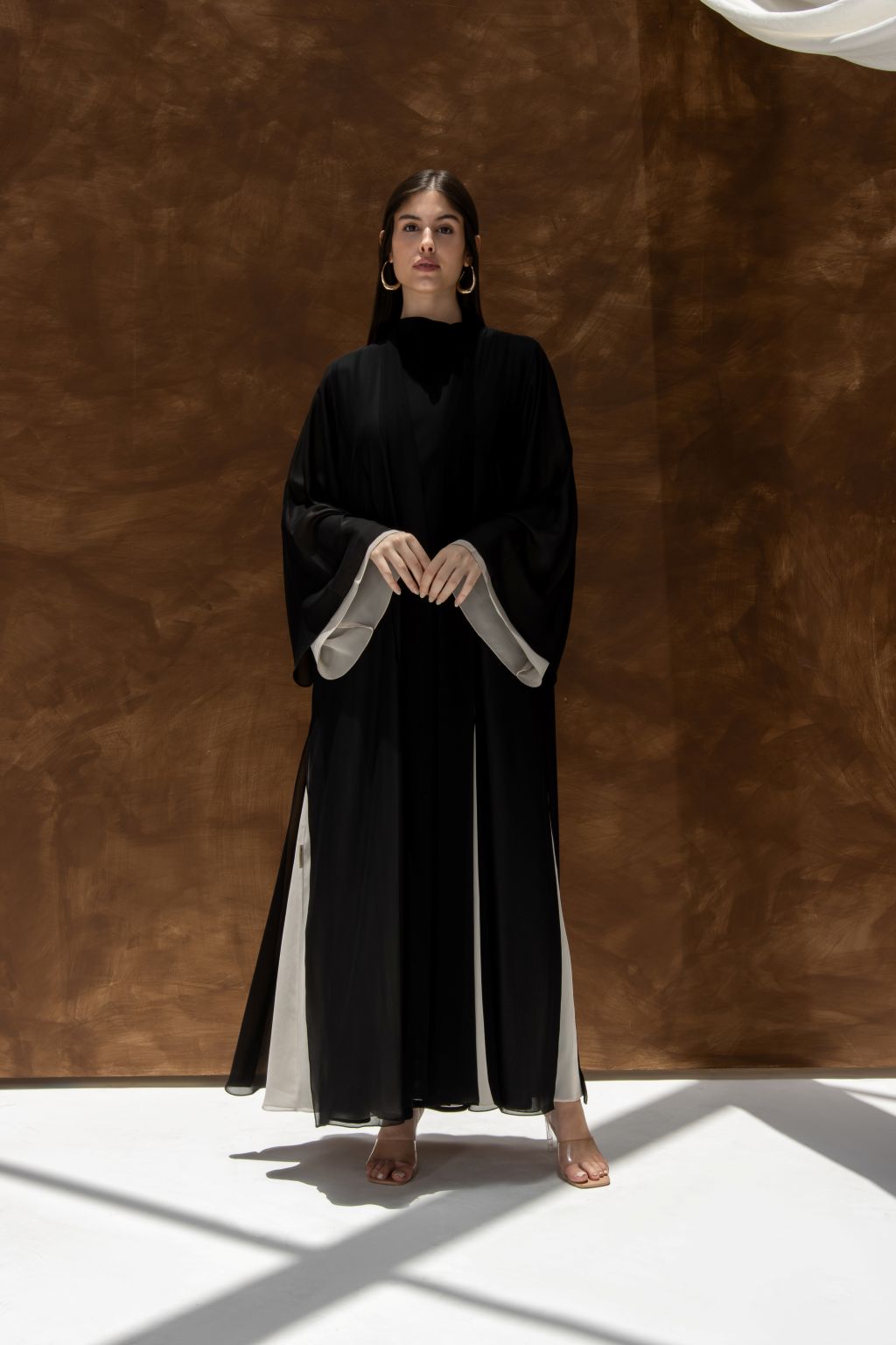 Selected Lines Layered Grace Abaya in black with white inner layers worn by model against brown background