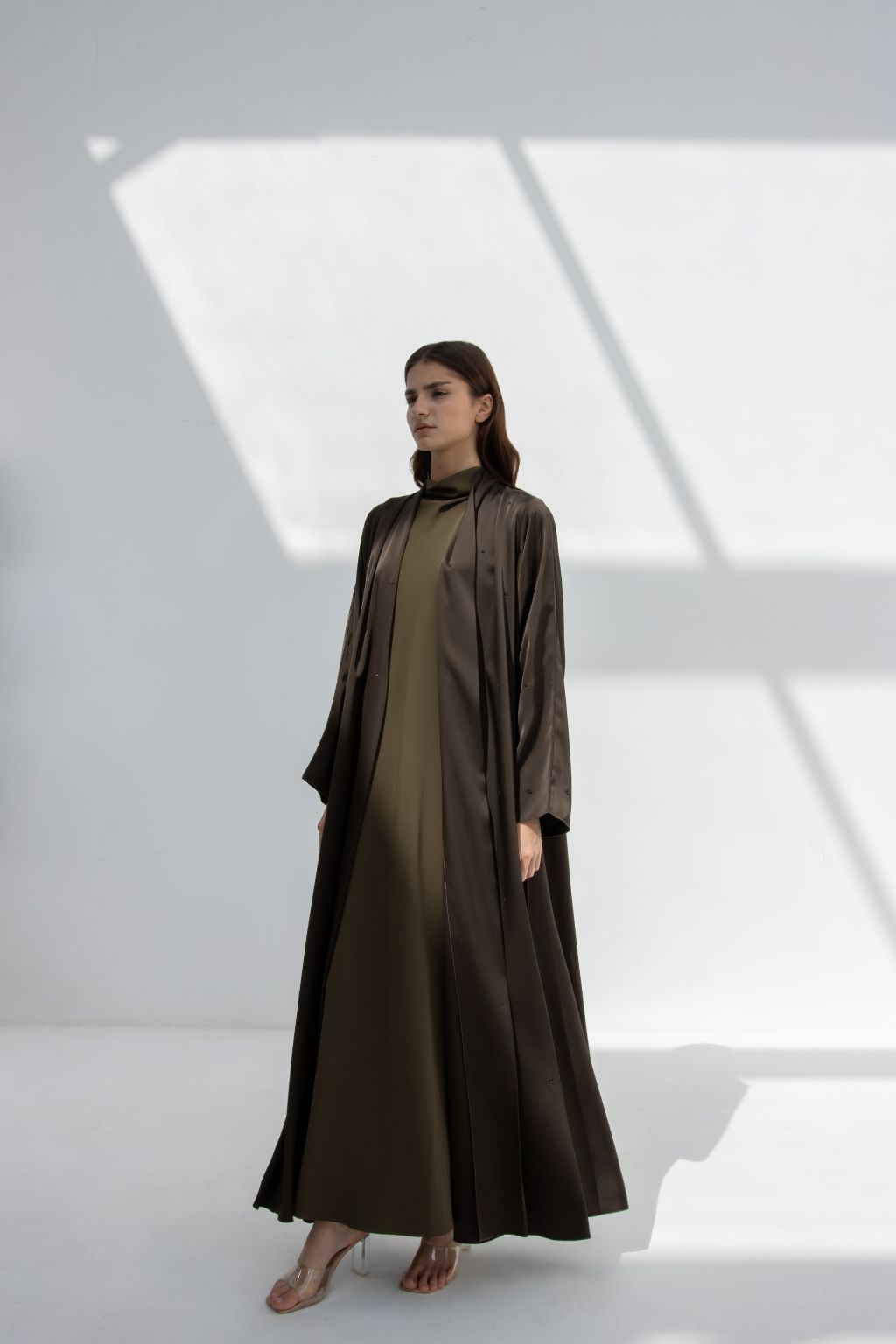 Selected Lines luxury evening stone abaya in dark and olive tones worn by model in bright studio