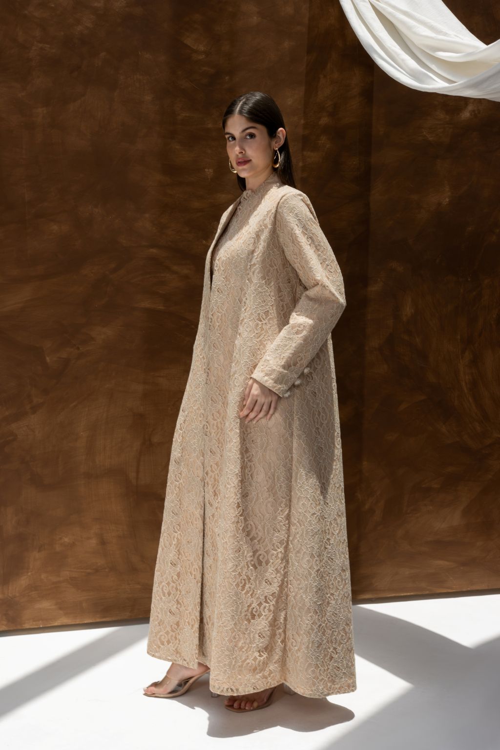 Selected Lines luxury lace Duntel Enchante' abaya in beige worn by woman with long sleeves and full length design