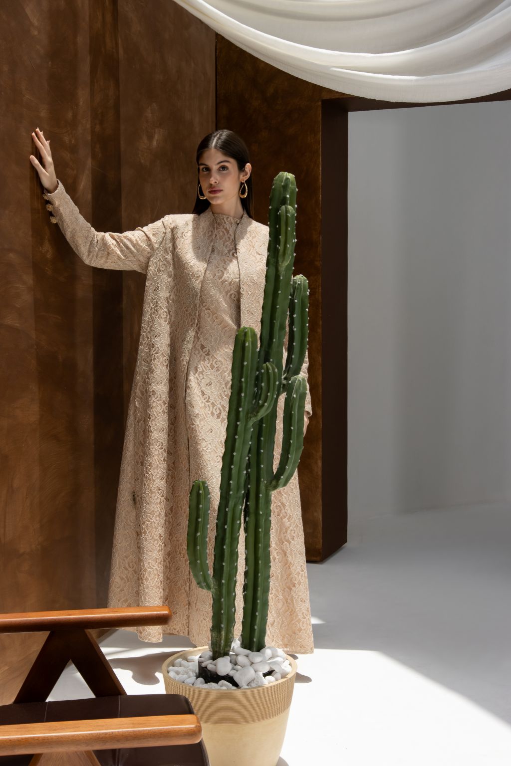 Selected Lines luxury lace Duntel Enchante abaya in beige worn by model standing near cactus plant