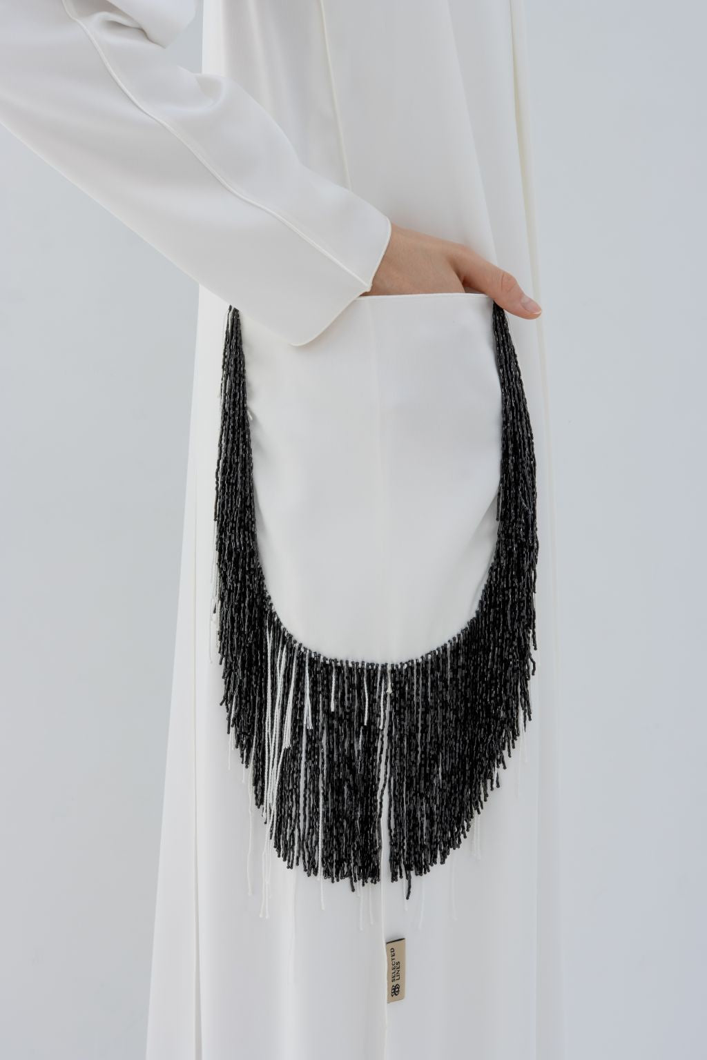 Selected Lines luxury pocket tassel abaya in white featuring black fringe tassel detail on pocket