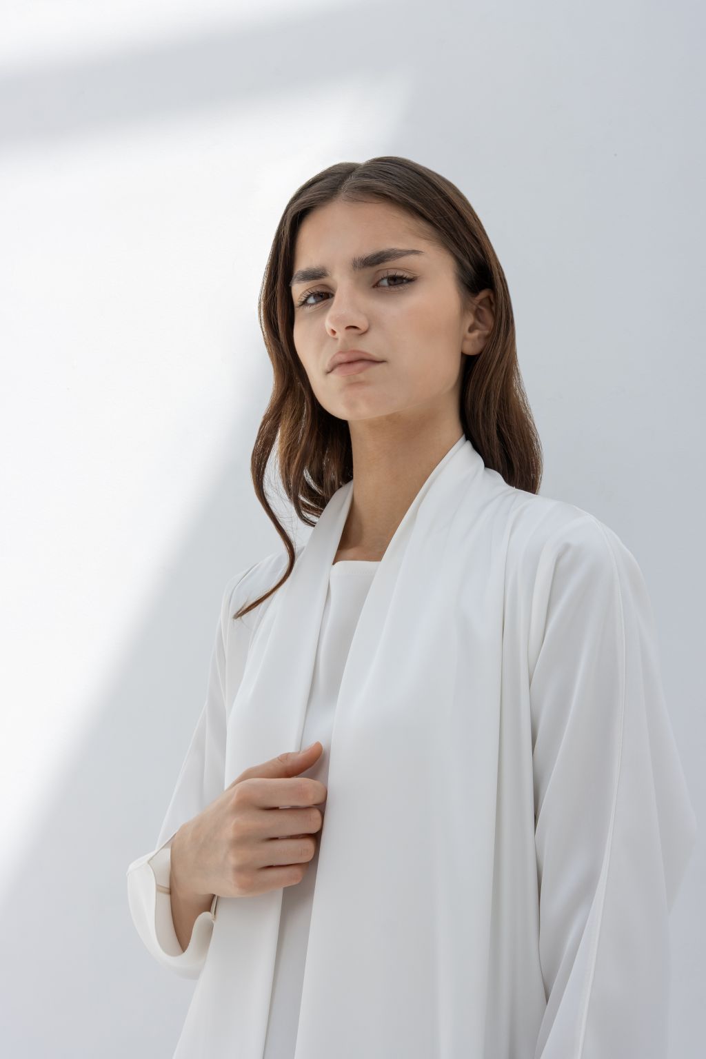 Selected Lines luxury pocket tassel abaya in white worn by a woman with long hair in natural light