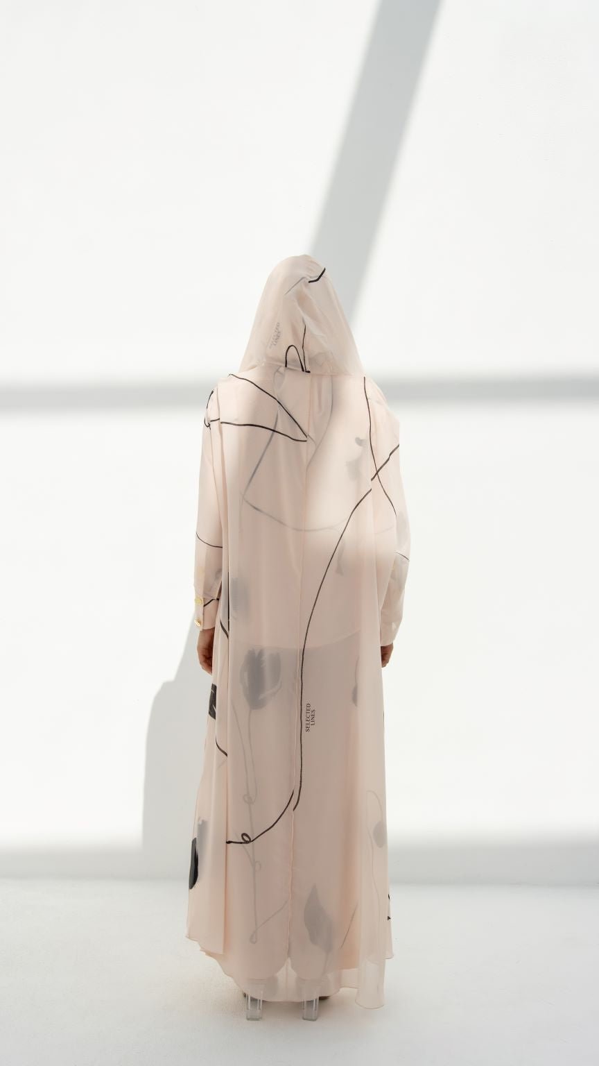 Selected Lines modest hoodie abaya in light fabric with abstract black line design viewed from the back