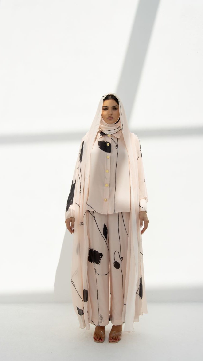 Selected Lines modest hoodie abaya in light pink with black abstract floral design and gold buttons