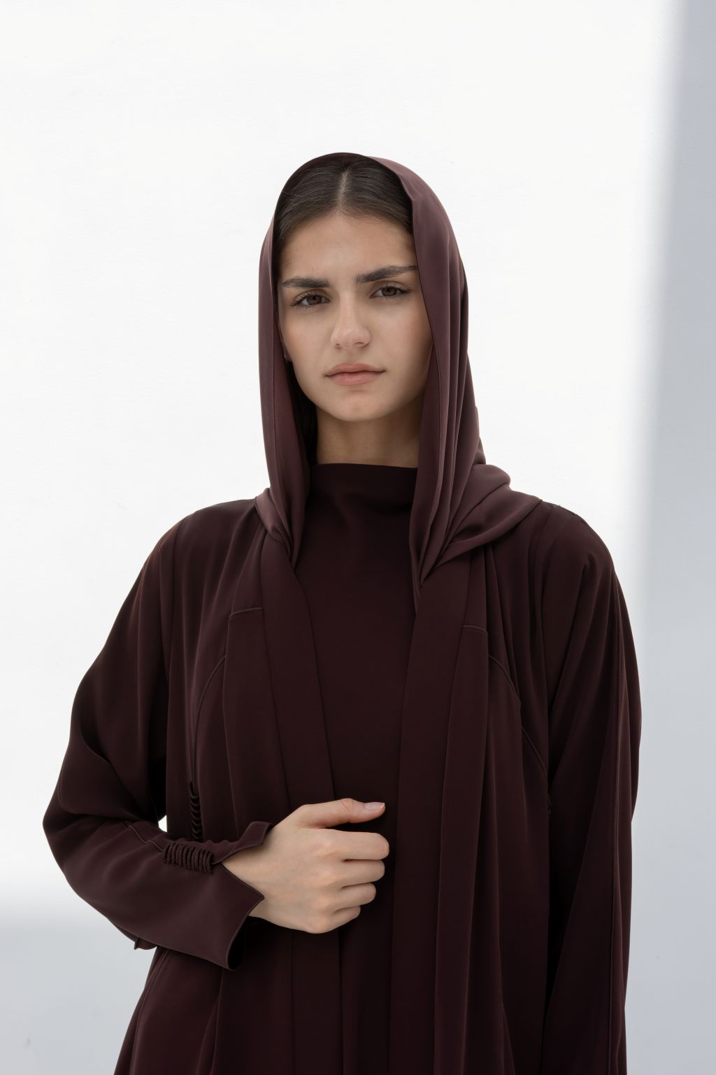 Elegant model wearing a premium handcrafted abaya in deep burgundy with a matching hood