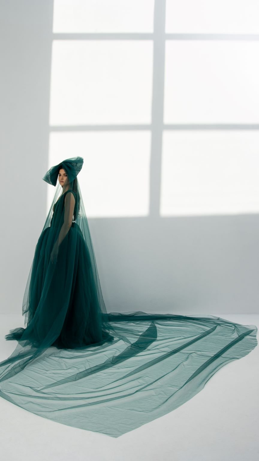 Elegant model in a teal refined bow party dress with flowing tulle and matching veil