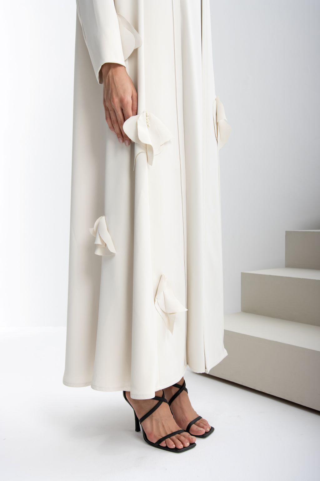 Elegant cream refined luxury evening abaya featuring delicate floral accents and paired with stylish heels