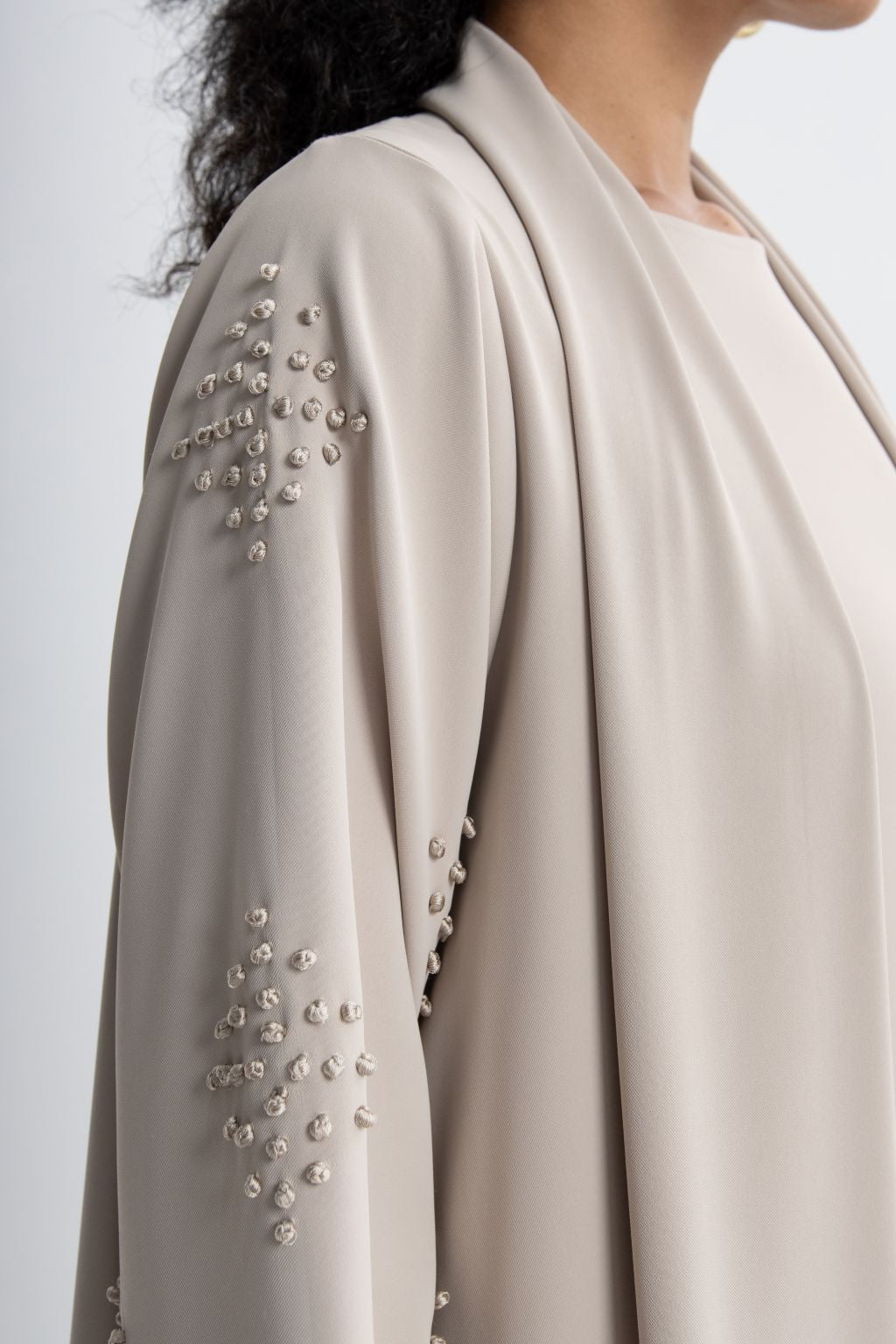 Refined neutral evening abaya with intricate beaded embellishments on the sleeves