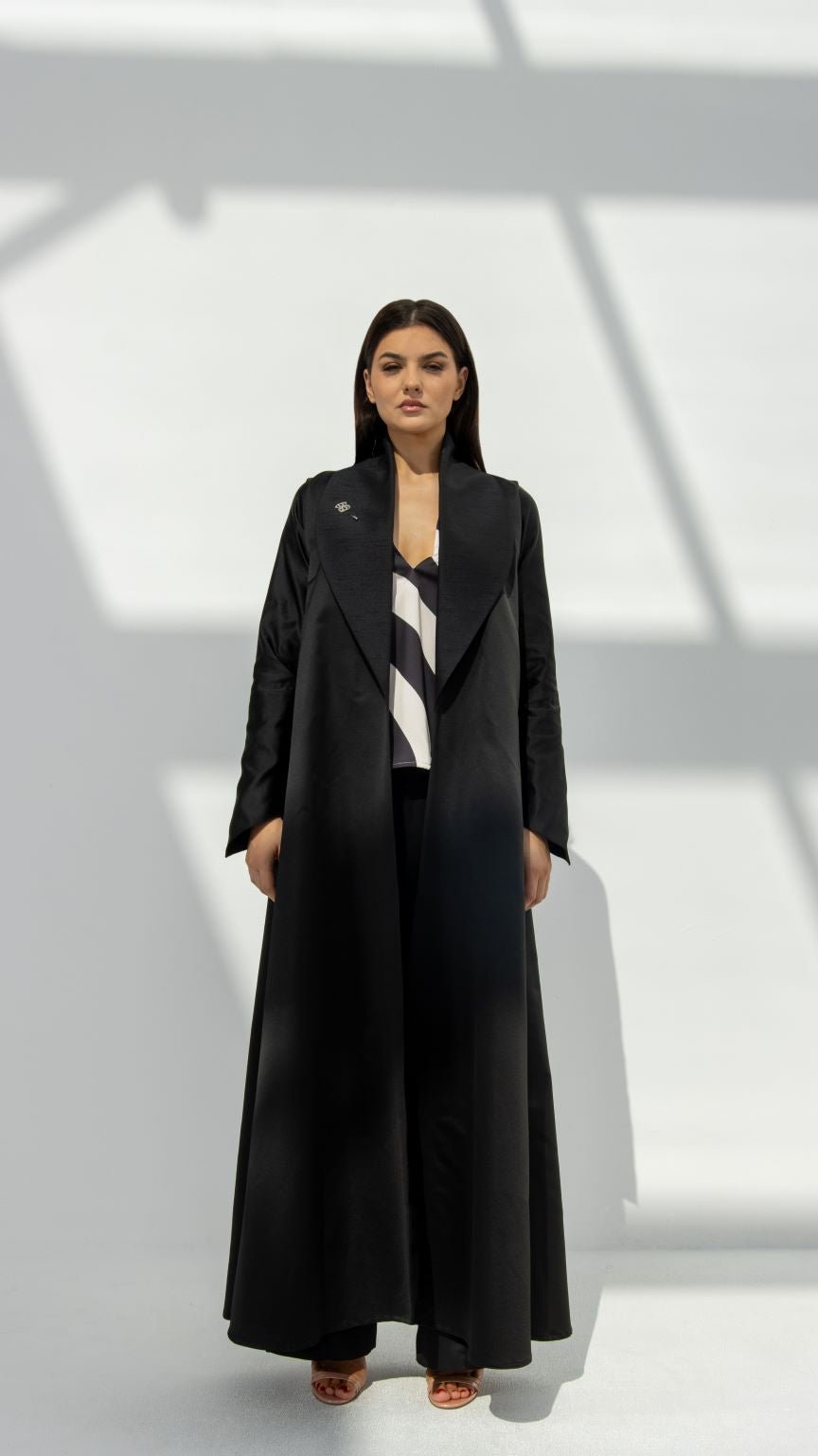 Front view of Smart Abaya in black matte and shiny fabric with signature silver logo brooch | Selected Lines