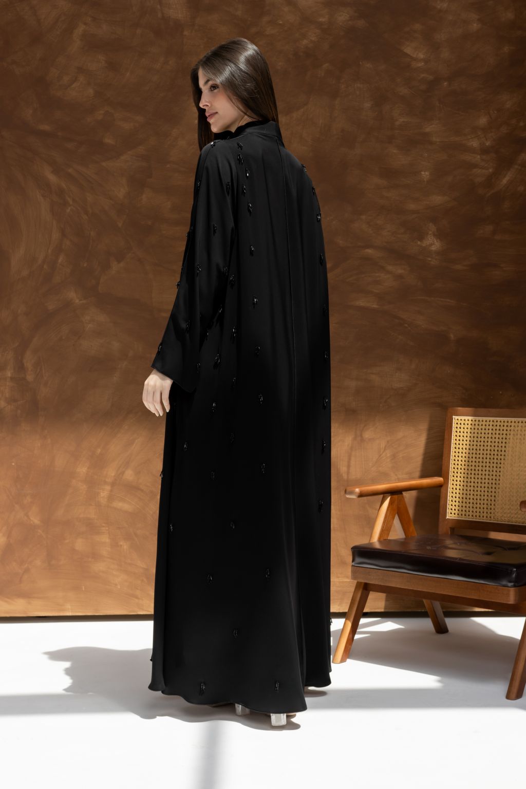 Selected Lines timeless black abaya gown with subtle embellishments worn by woman standing indoors