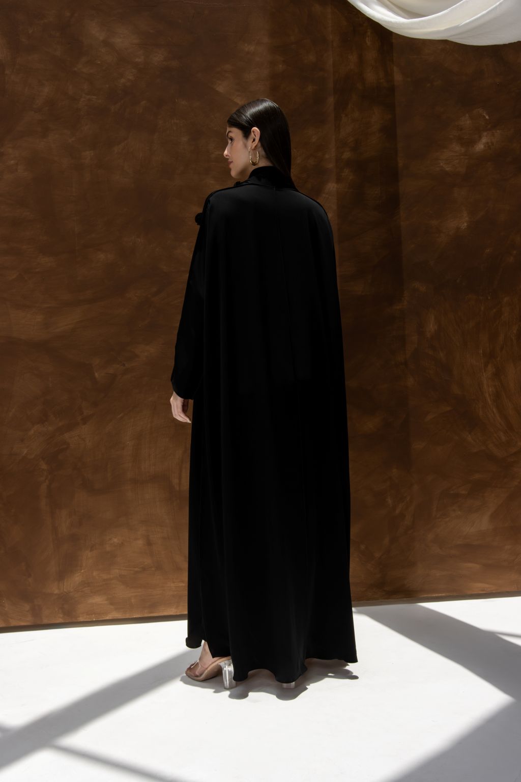 Selected Lines black abaya featuring a blooming Bahraini abaya elegant design worn by woman in minimalist setting
