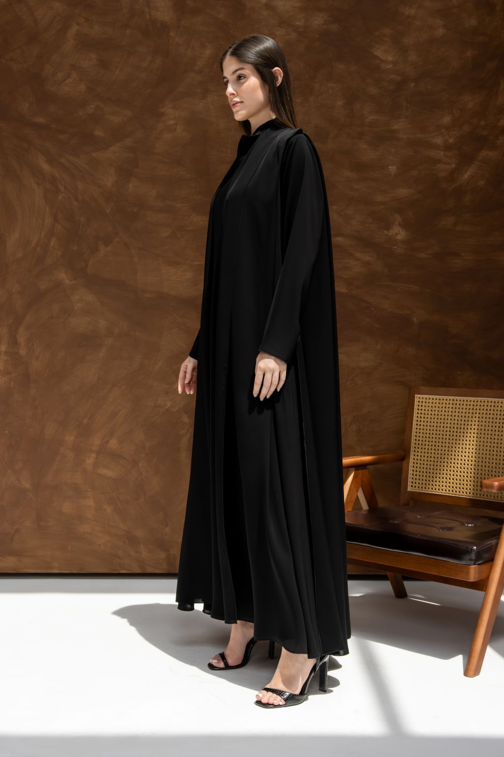 Model wearing an elegant black abaya with a flowing design and long sleeves