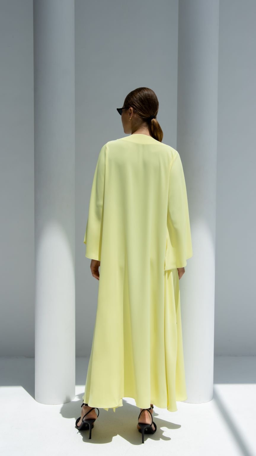 Back view of a woman in a stylish yellow elegant chain dress with flowy sleeves