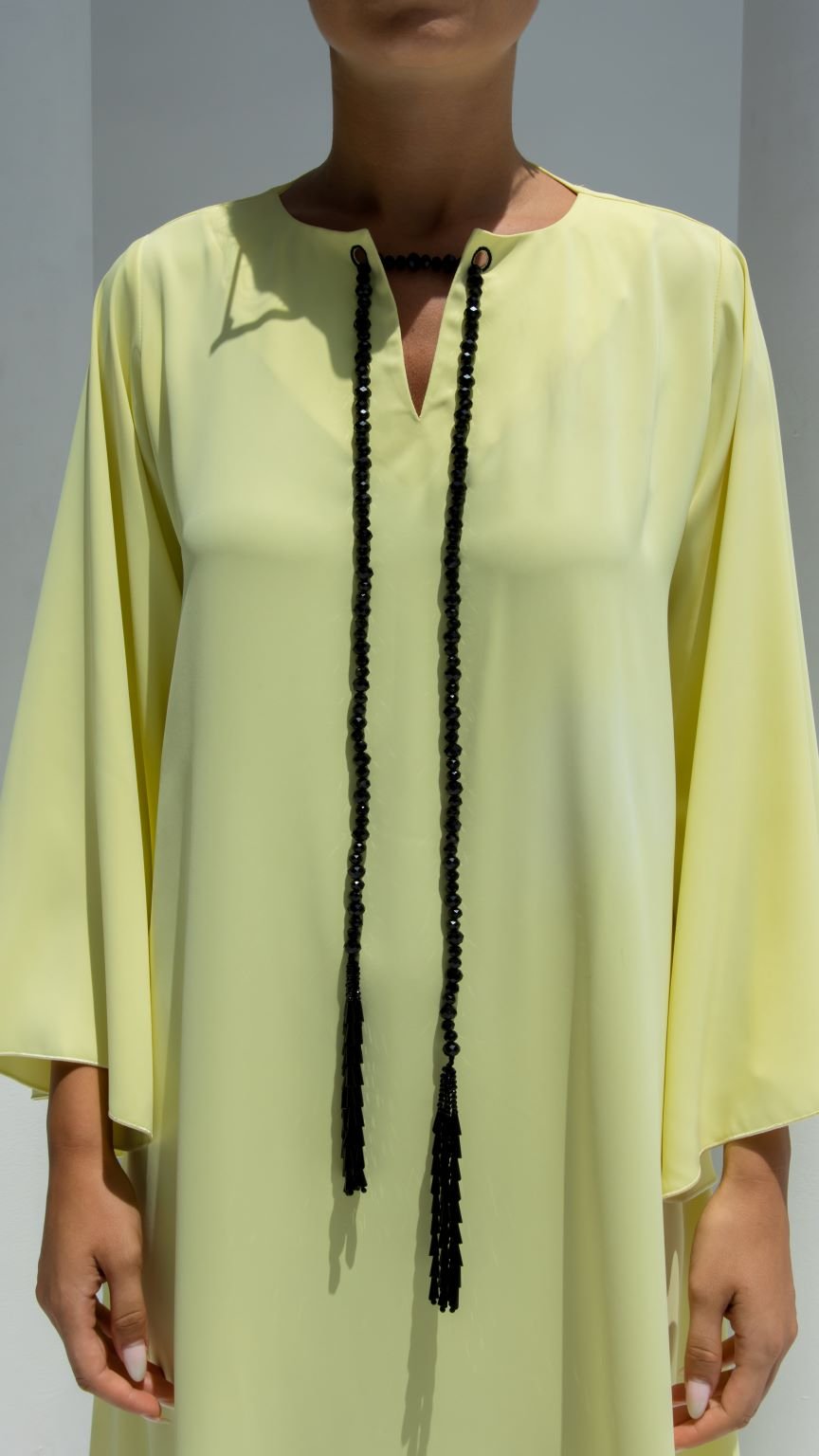 Elegant chain dress in soft yellow with unique tassel detailing for a chic look