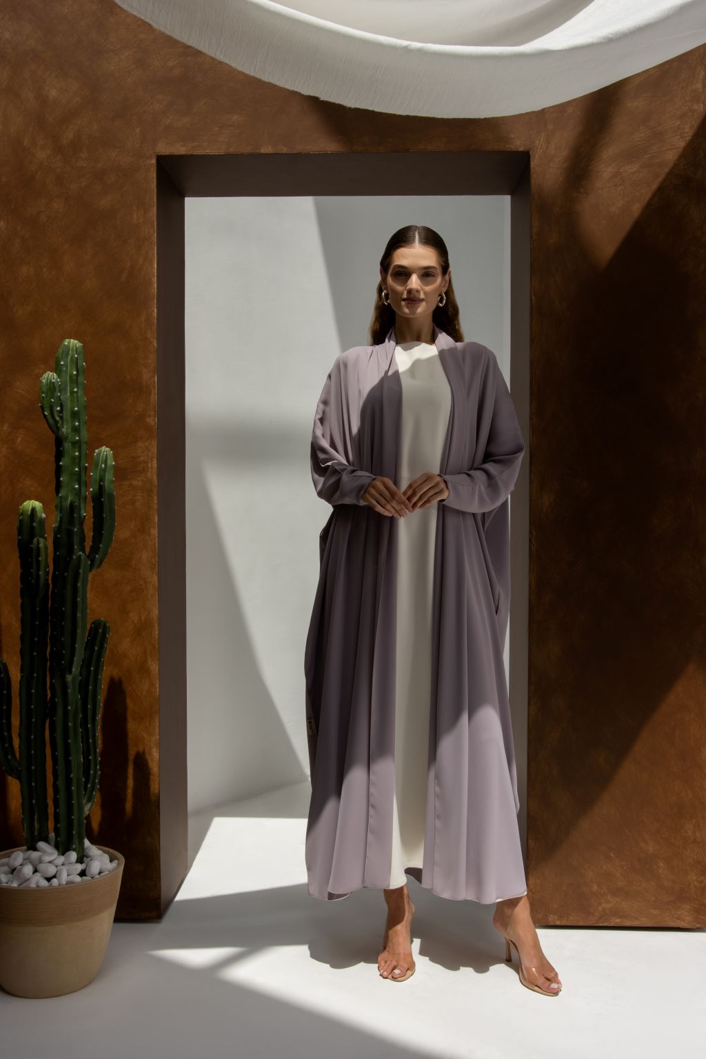 Woman wearing an elegant signature abaya by Selected Lines in a lavender shade standing indoors
