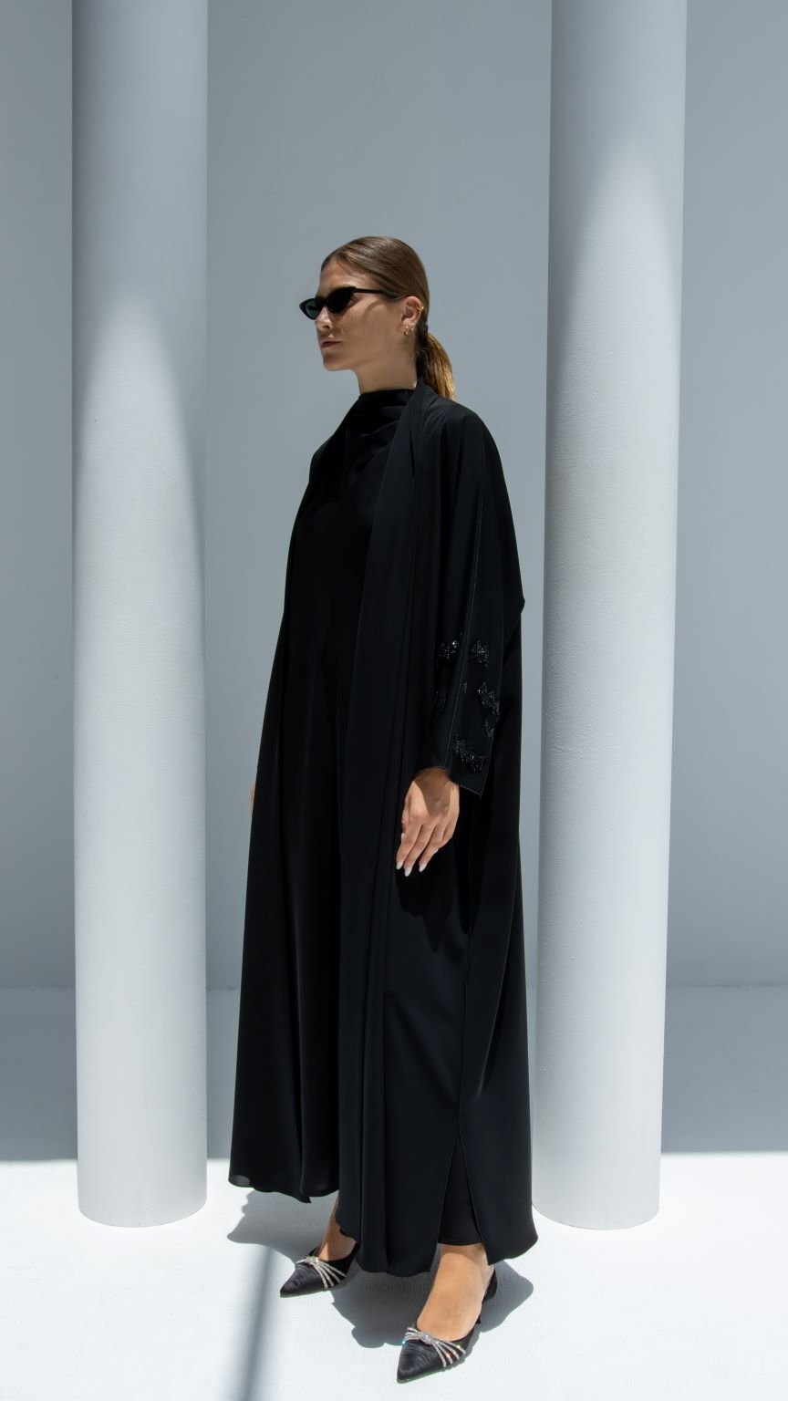 Model wearing Julia Abaya luxury in black with stylish sunglasses and chic shoes in a modern setting
