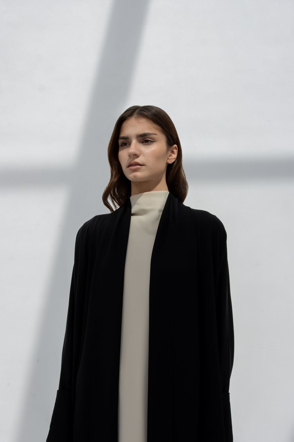 Model wearing a luxury black abaya over a neutral outfit for a modern, elegant look