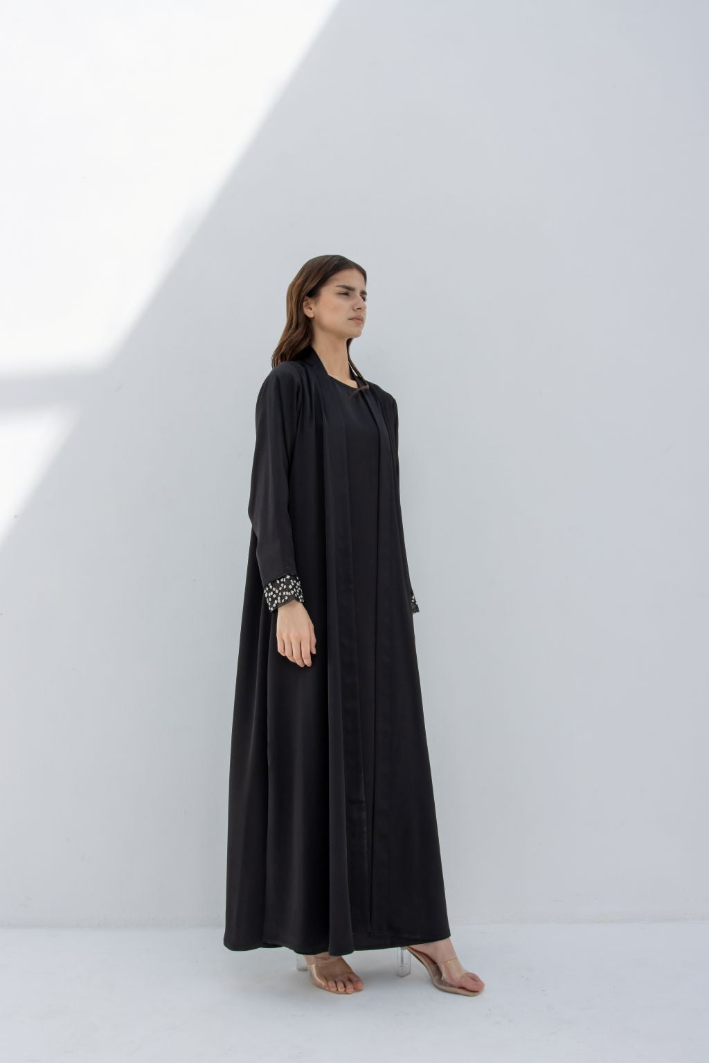 Selected Lines luxury silver crystal abaya in black with crystal cuff details, worn by standing woman