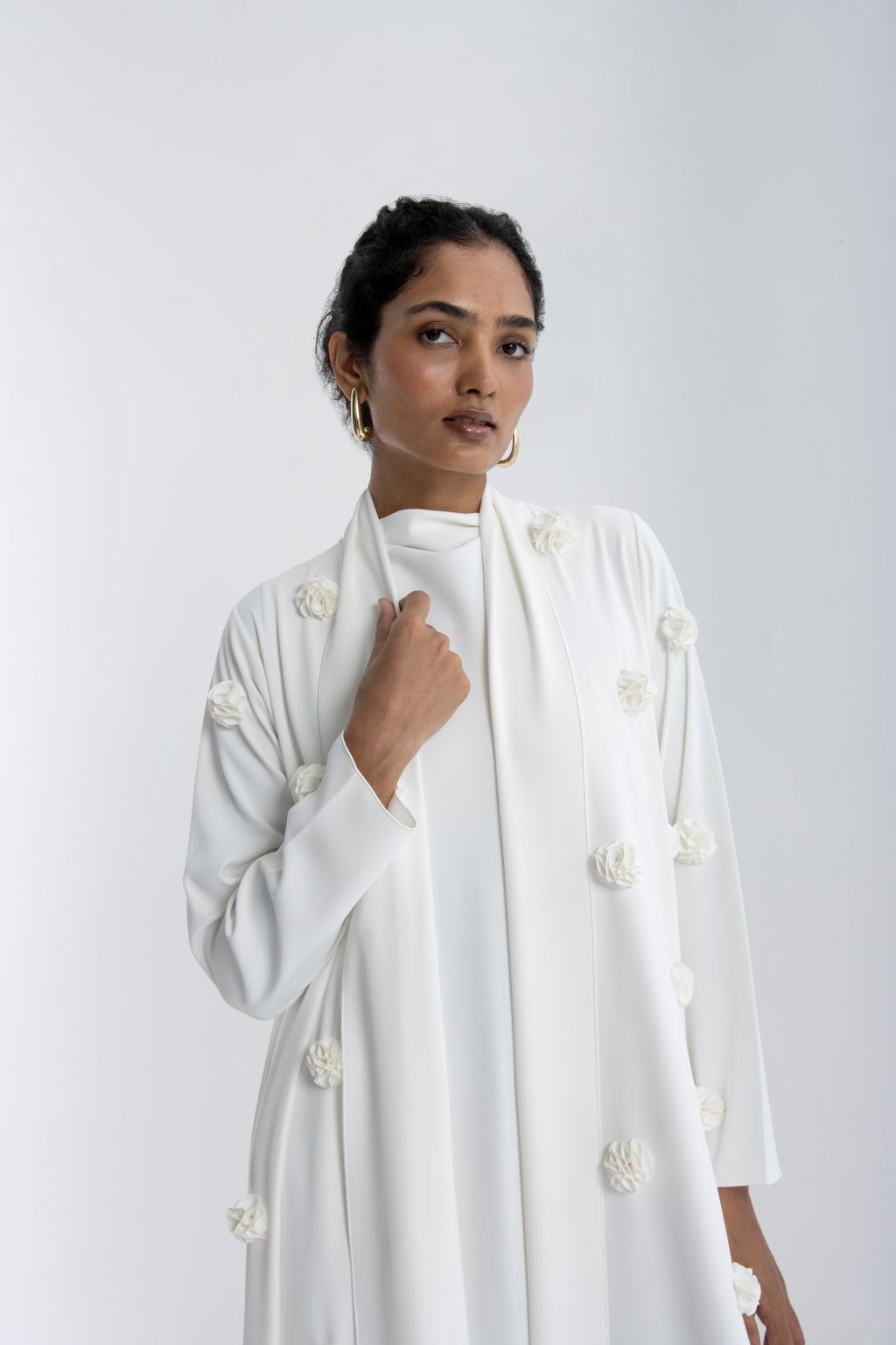 Elegant woman wearing a luxury white abaya with rose embroidery, showcasing a modern design and delicate details