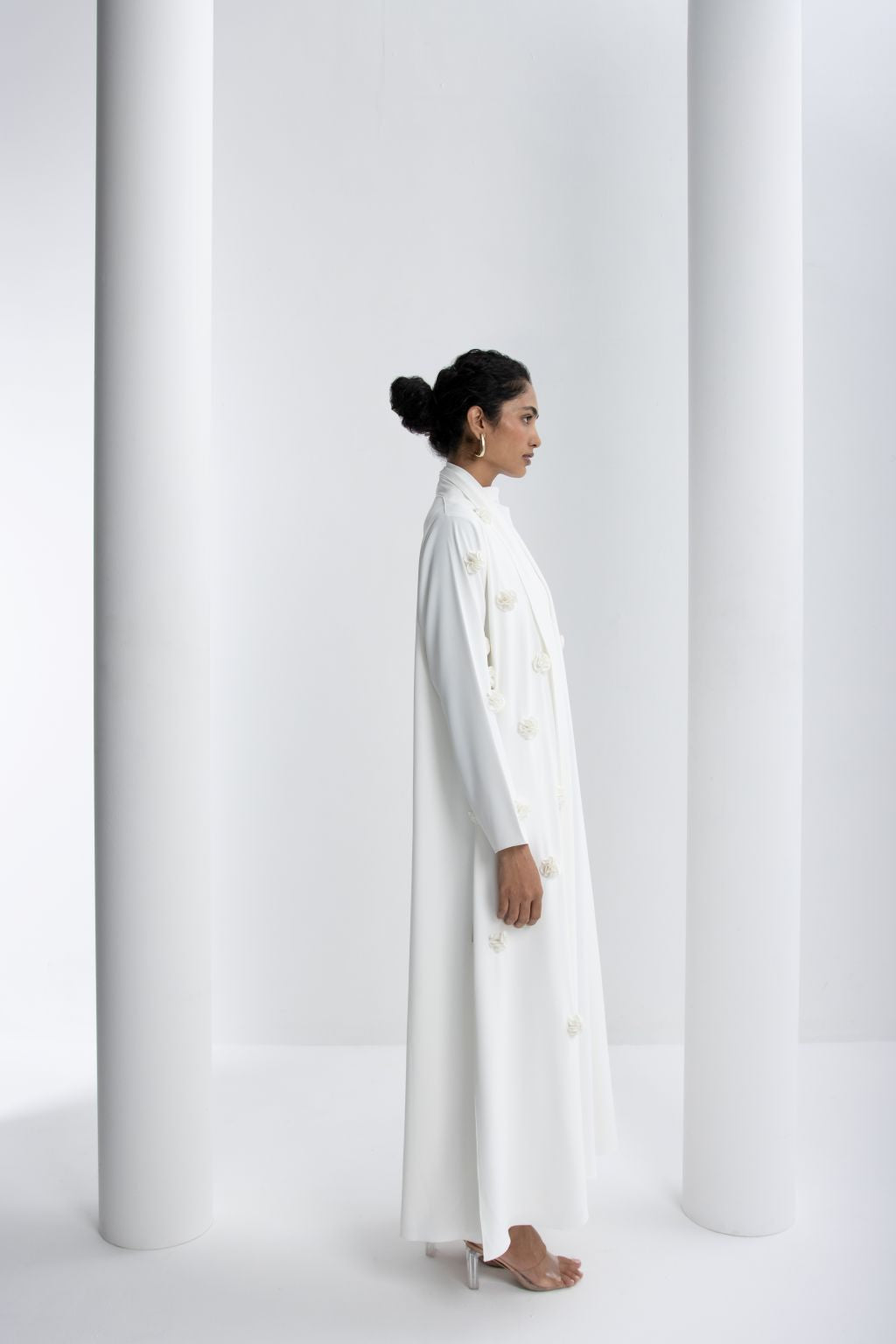 Luxury white abaya with rose embroidery elegantly draping on a model against a minimalist background