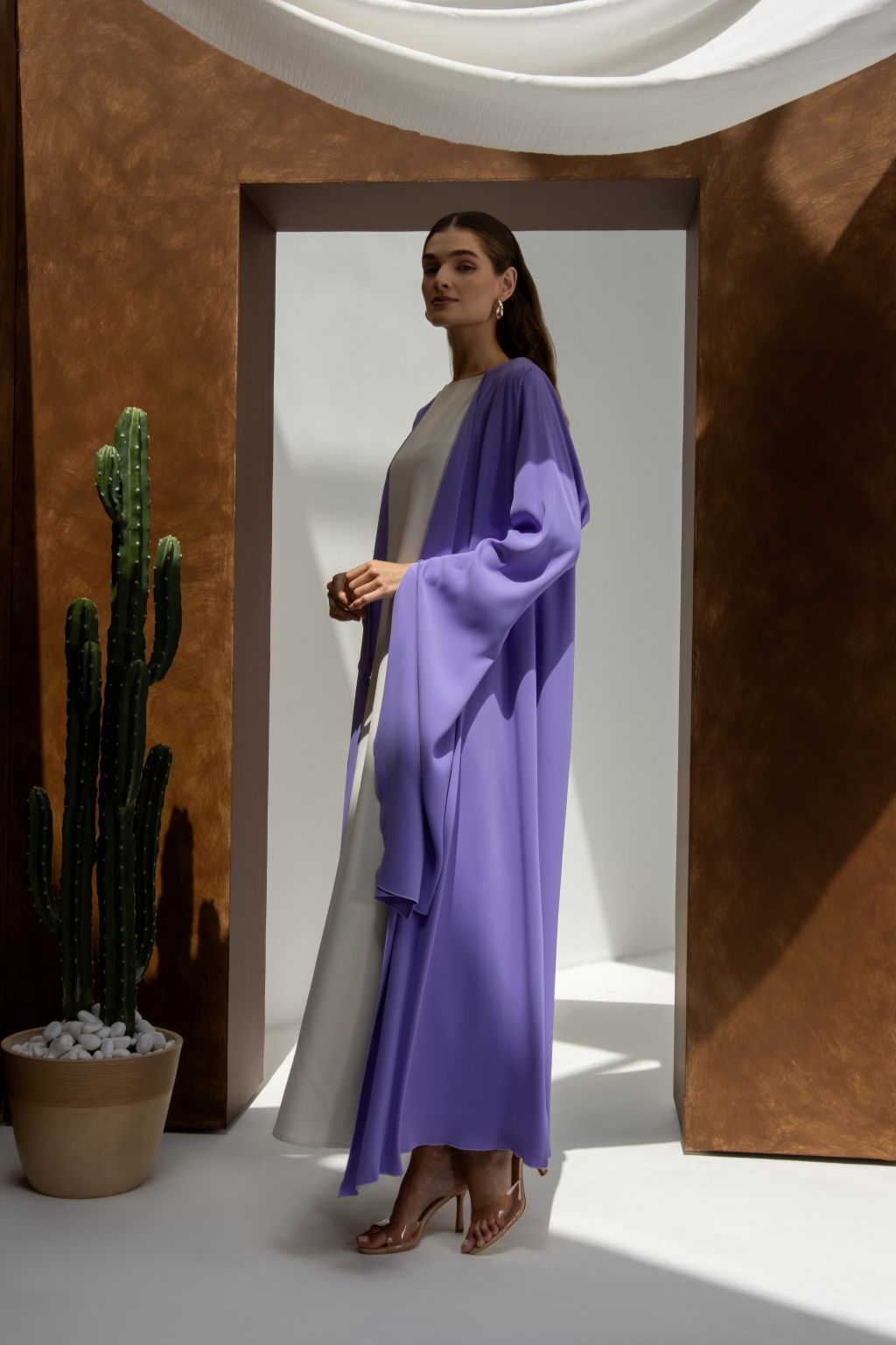 Selected Lines Onz SLC Signature robe in purple worn over white dress with high heels and cactus in background