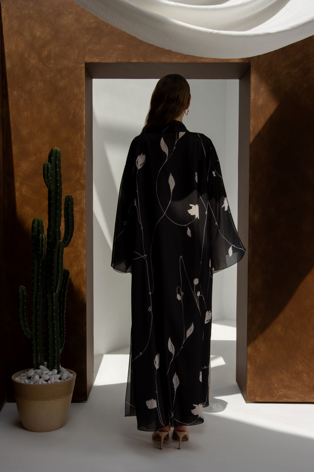 Selected Lines signature leaves black abaya with white leaf patterns shown from the back on a model