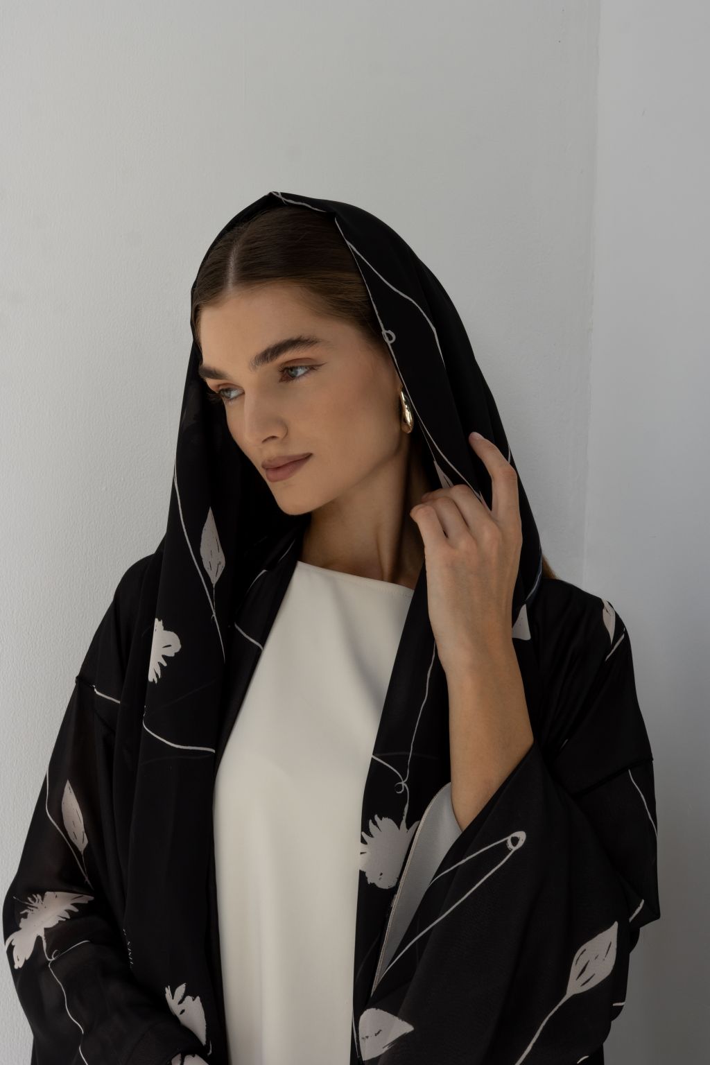 Selected Lines signature leaves black abaya worn by a woman with hooded style and white floral patterns