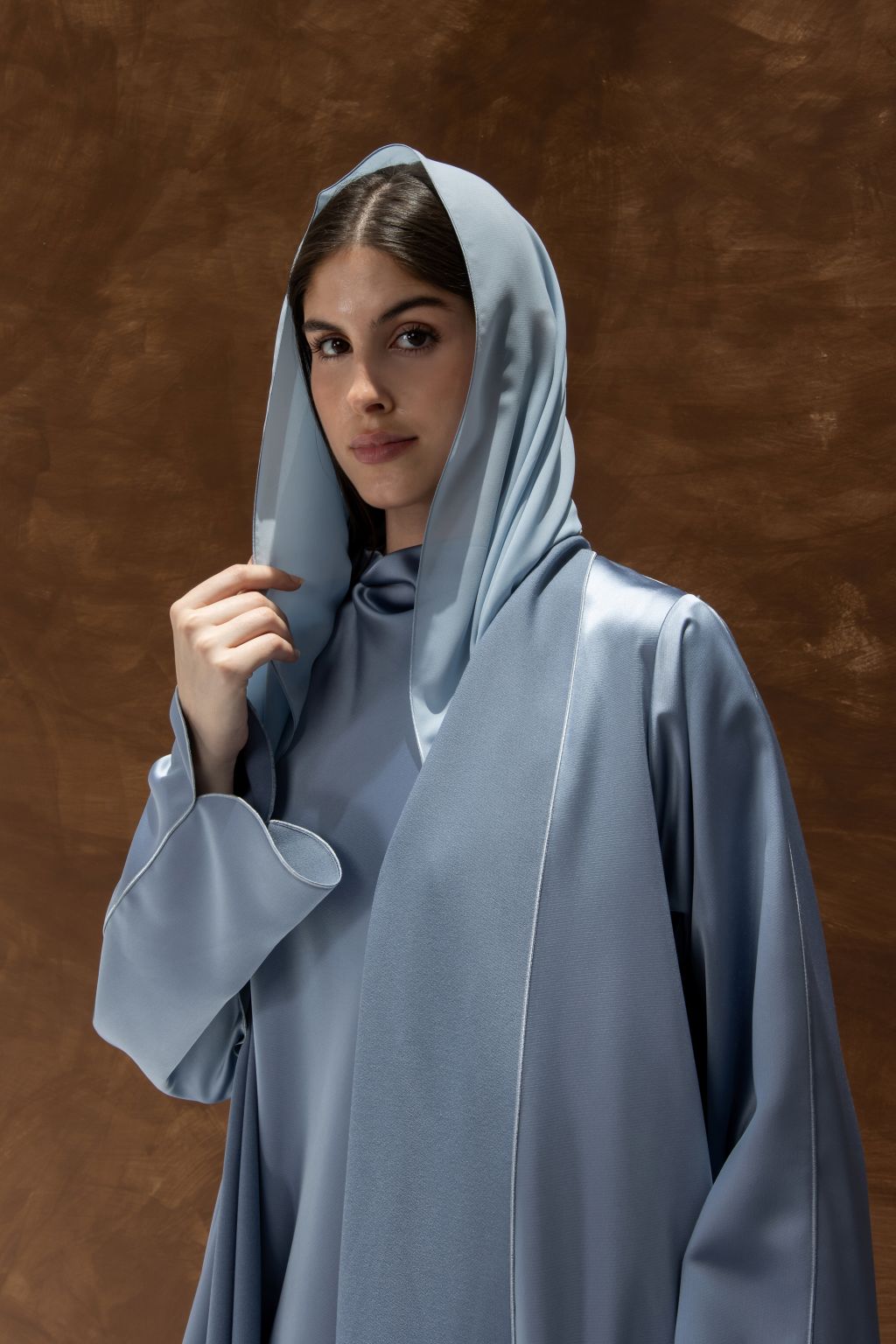 Selected Lines silhouette abaya with refined design in soft blue satin fabric worn by a woman