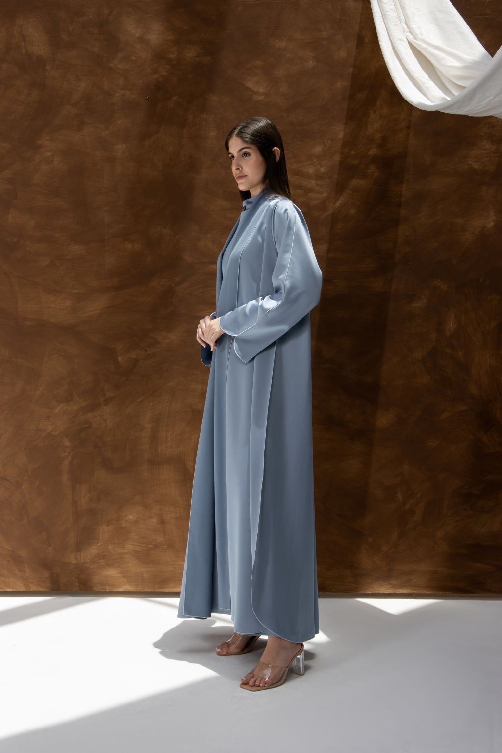 Selected Lines silhouette abaya with refined design in soft blue fabric worn by model standing sideways