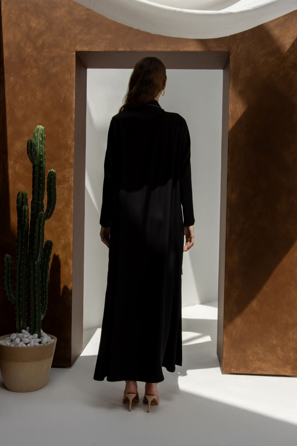 Back view of woman wearing black threaded Bloom floral abaya for women by Selected Lines in modern setting