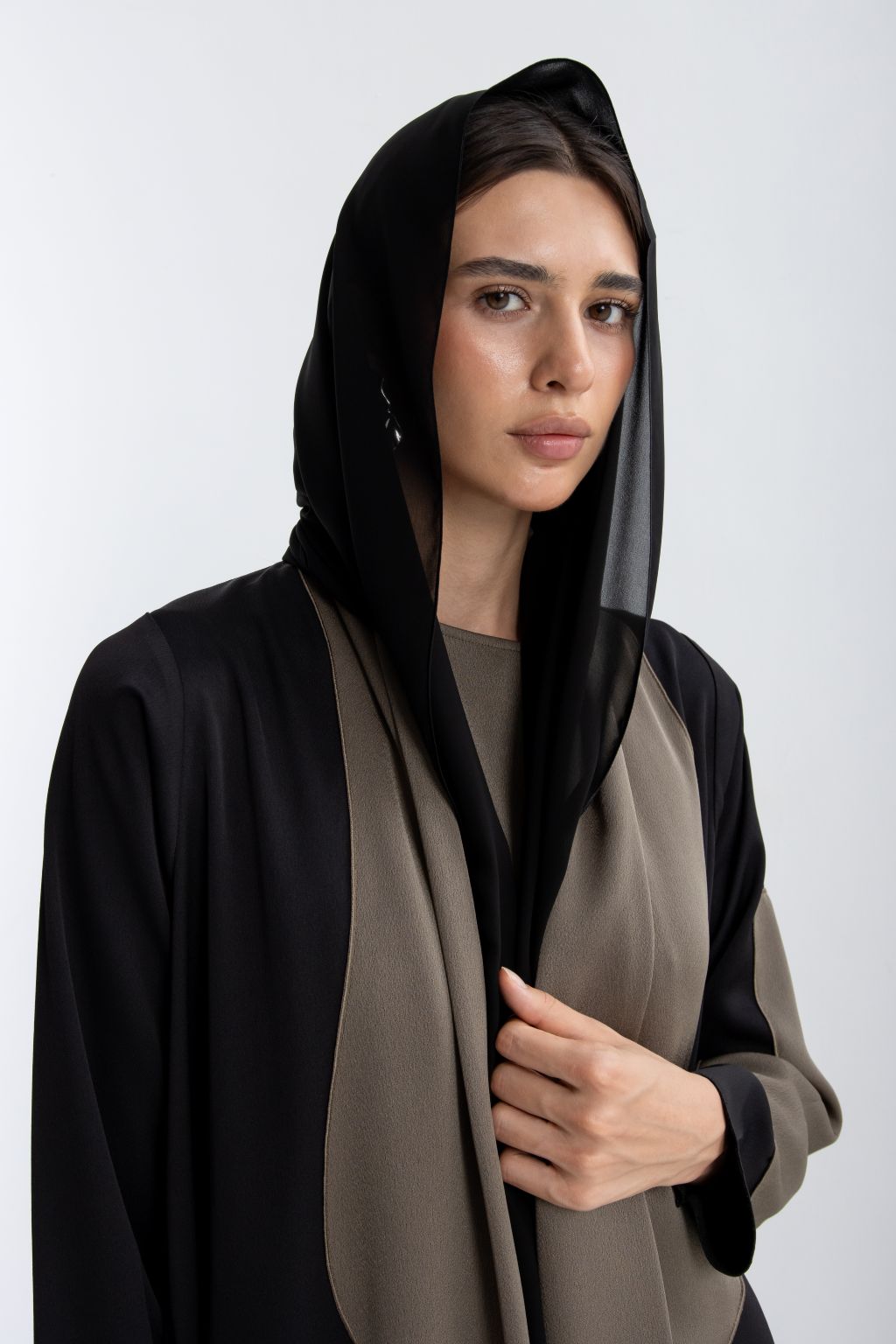 Elegant woman wearing a timeless handcrafted abaya in black and beige with a flowing silhouette