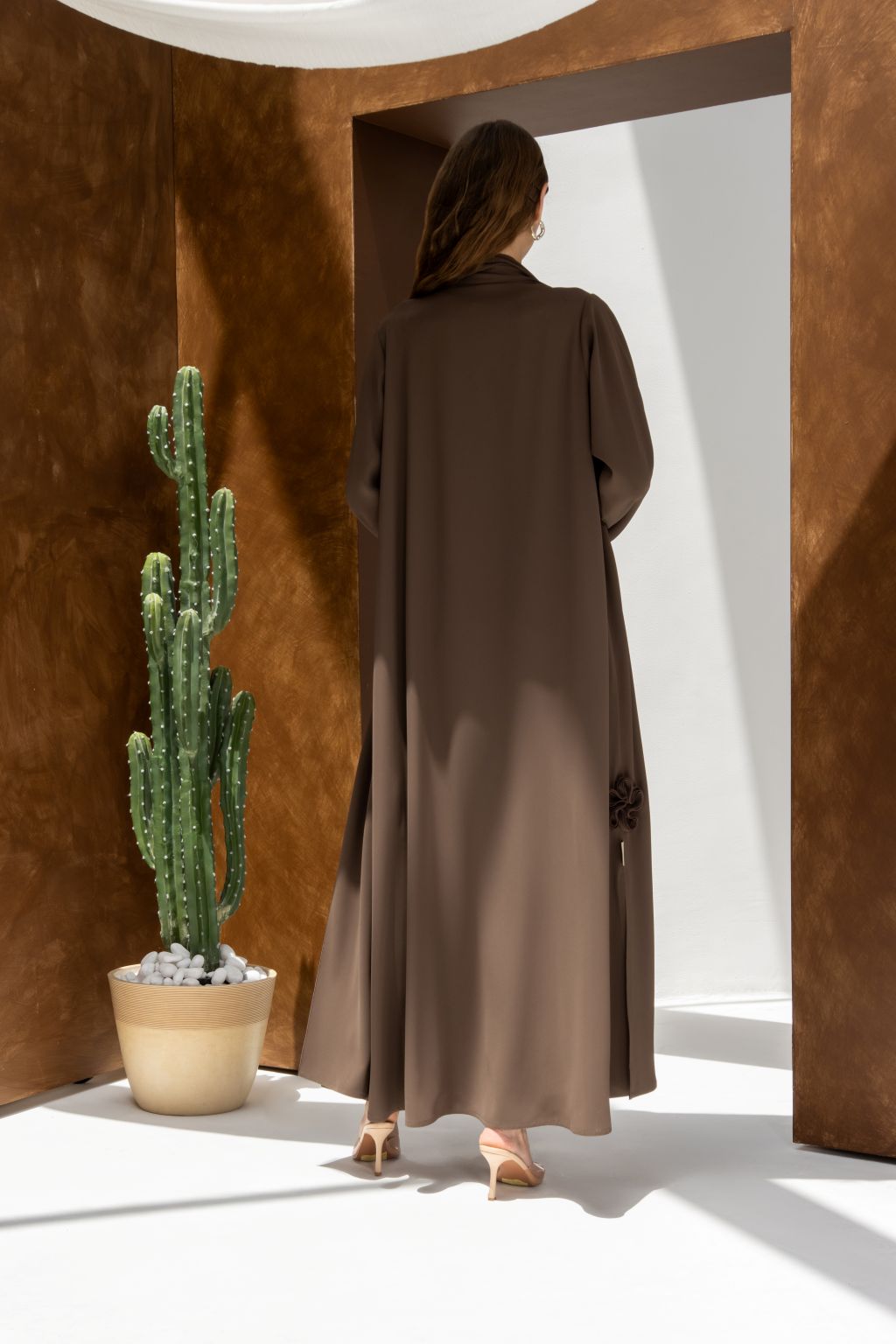 Selected Lines brown abaya worn by model standing near cactus showcasing timeless modest evening wear