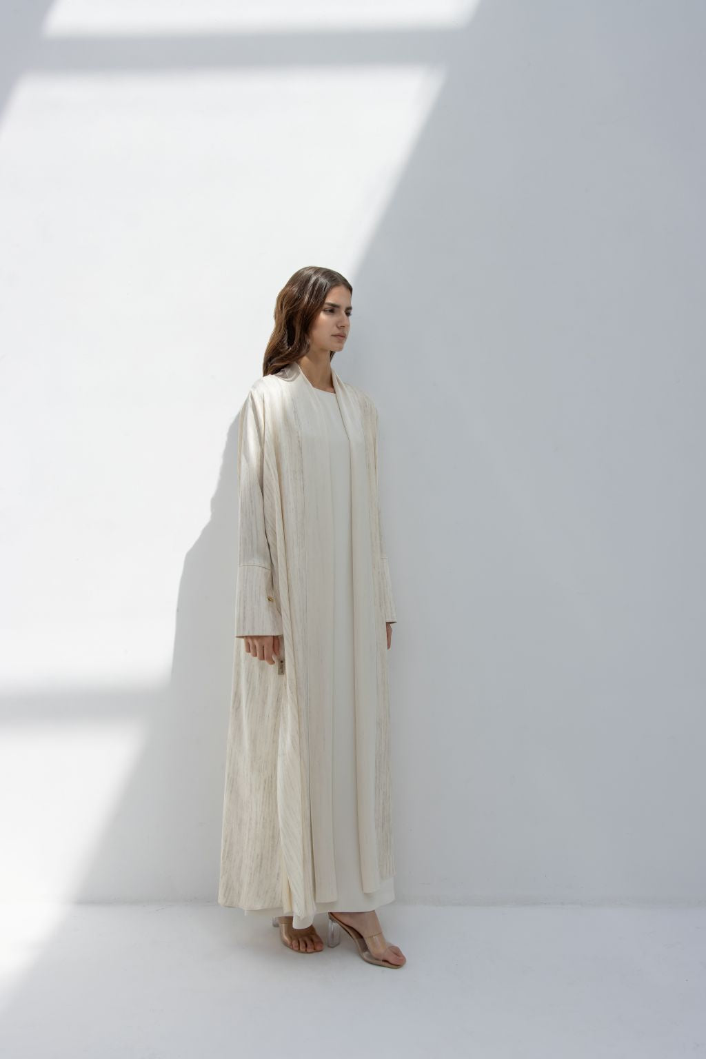 Selected Lines elegant printed abaya in a light cream color worn by a woman in a bright minimalist setting